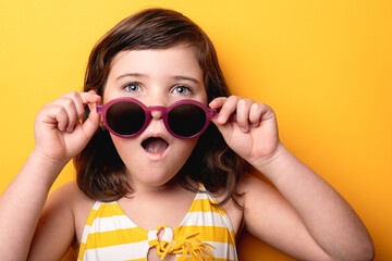 Young girl expressing surprise holding large sunglasses