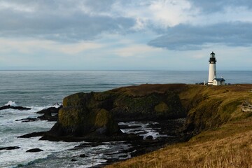 White lighthouse on the coast against the cloudy sky in summer