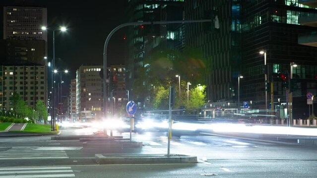 Timelapse  pedoni che attraversano la strada ad un semaforo, mentre auto veloci creano scie luminose in entrambi i sensi di marcia
