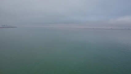 Gray footage of misty cloudy sky over the sea near sandy beach at sunset
