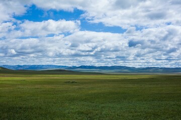Scenic landscape featuring rolling fields with a few scattered clouds in the sky