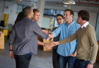 Fototapeta premium Business people, handshake and group with meeting at startup for collaboration, b2b deal or agreement. Men, women and shaking hands with smile in scrum, kindness and respect at creative media agency