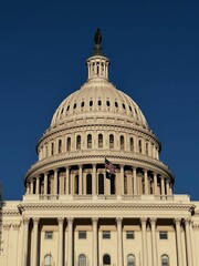 Obraz premium Blue sky over the US Capitol Building with waving national flag - Washington DC, United States