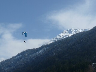 Vibrant blue parasail soaring in the sky against a backdrop of majestic mountains