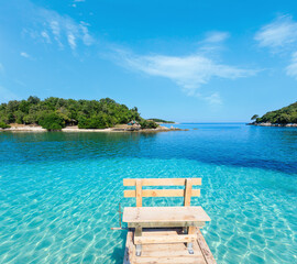 Beautiful Ionian Sea with clear turquoise water, wooden pier and morning summer coast view from beach (Ksamil, Albania).