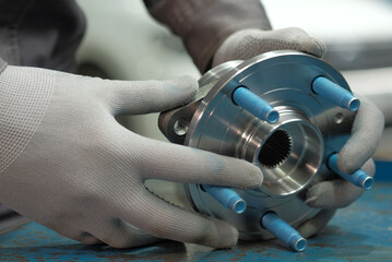 Car parts.The wheel hub is rear.An auto mechanic holds a new hub in his hands, checks the part...