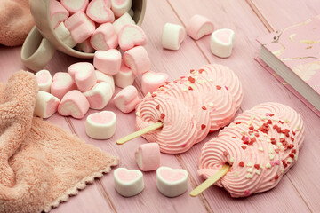 Pink dessert. Sweet marshmallow hearts and two pink soufflé cakes on a wooden table.