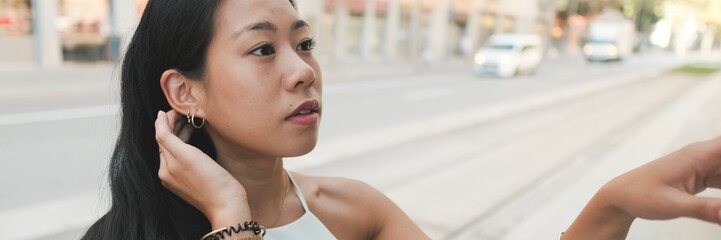 Close-up of pretty girl standing at public transport stop, analyzing the schedule of transport on...