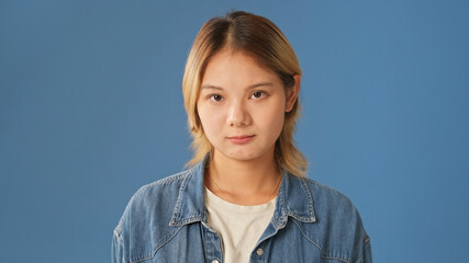 Close-up of young woman dressed in denim shirt listens carefully and disagrees looking at camera...