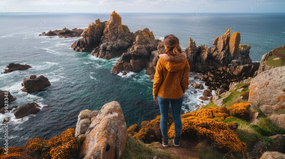 Poster a woman standing on a cliff with a view of the ocean. suitable for travel and adventure concepts