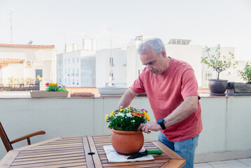 Mature man gardening on rooftop balcony in the city