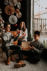 Kids holiday magic: Two brothers and sister playing with lanterns by the Christmas tree