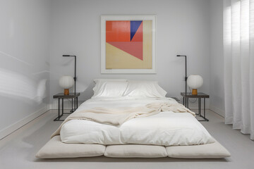 Minimalist bedroom with a low bed, white linens, and a geometric painting. Sleek bedside tables and lamps.