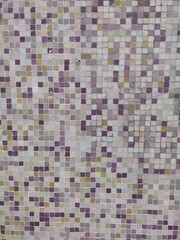 Vertical shot of colorful mosaic display. Wall decorated with different gradations of violet, beige colored mosaic stones. Close up of dark and light shaded purple, yellow and grey tiny tessellation