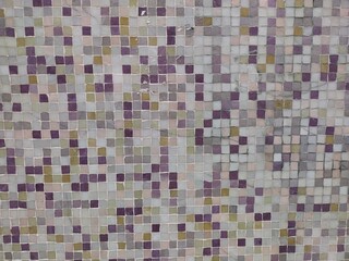 Colorful mosaic display. Wall decorated with different gradations of violet, beige colored tiny mosaic stones. Close up of dark and light shaded purple, yellow and grey tiny tessellation