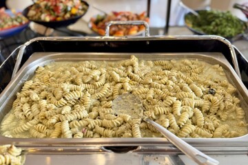 A plate of delicious pasta sits on the table with a spoon in it, ready to be enjoyed. The dish is made with fresh ingredients and is a classic Italian cuisine recipe