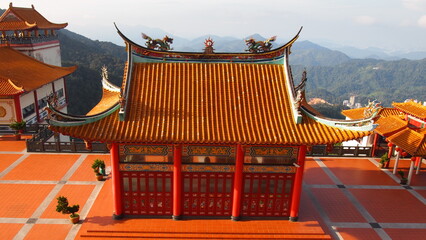 A drone view of a buddhist temple in the mountains; red and orange color buddhist temple structure; religious photography; drone view; aerial view