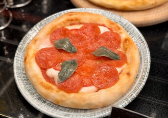 Top view of delicious sliced pepperoni pizza on wooden dish on the table at the restaurant. Close-up