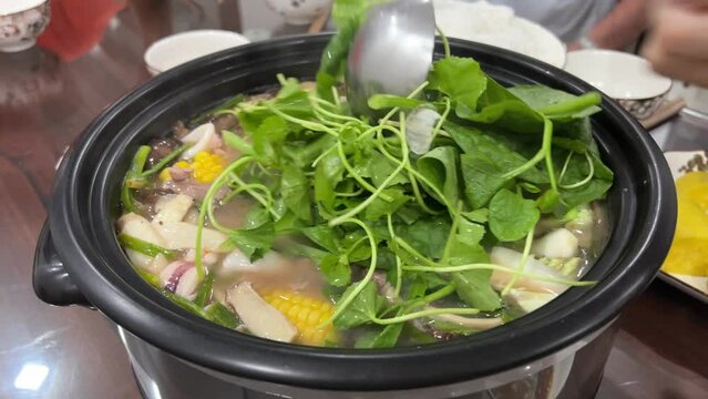 Vietnamese food shells mussels rapan fish cooking Vietnamese soup with green leaves and pieces. Cooking soup with herbs in a restaurant