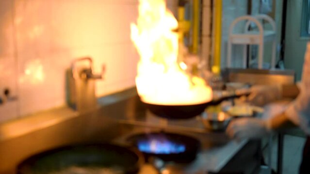Blurred of professional chef cook flambe style, Chef frying mixing vegetable on gas hob in the kitchen restaurant