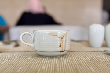 Dirty cup after drinking coffee is located on the restaurant table. Close-up