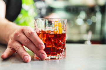 Close-up of a hand resting on a bar next to a glass of whiskey with ice, highlighting leisure time