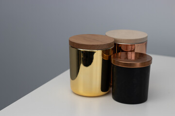 three metallic candle jars with wooden lids sitting on a white table with a white background, candles, jars, product mockups