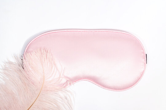 Pink Silk Sleep Mask and Feather on White Background