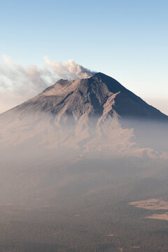 Erupting volcano with ash cloud in serene sky