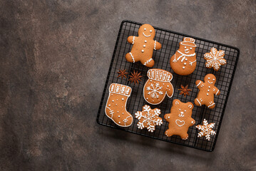Set of Christmas gingerbread cookies on a cooling rack, brown rustic background. Top view, flat lay, copy space.
