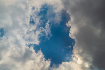 A patch of blue sky shining through the diverging rain clouds. A symbol of the changes and inconstancy of the current state of affairs, the movement of masses and time