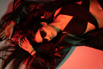 A woman is laying on her back in a black jacket with a black bikini top on