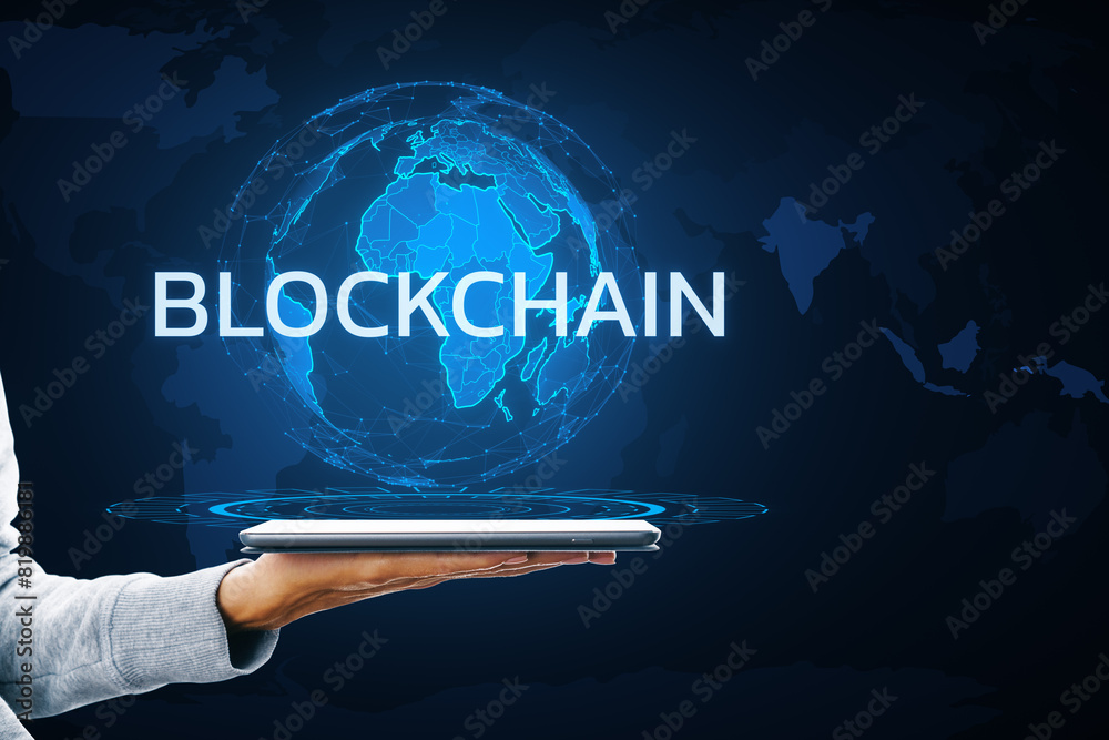Poster a person's hand holding a tablet displaying a holographic globe with the word blockchain on a dark b