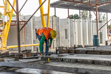 A male constructer or worker in safety vest is preparing steel bars to make concrete floor foundation in a factory