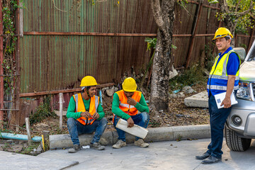 Team of civil engineers or workers in safety suits taking rest after a long day in a construction...