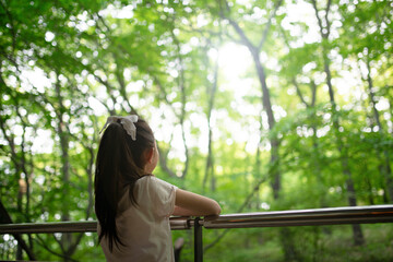 ベランダから森を眺める少女