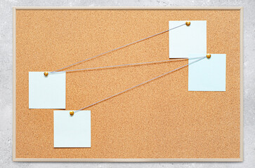 Blank paper notes are pinned to a cork board. The concept of detective investigation or training