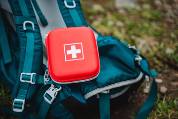 An electric blue first aid kit is placed on a blue backpack, surrounded by automotive exterior...