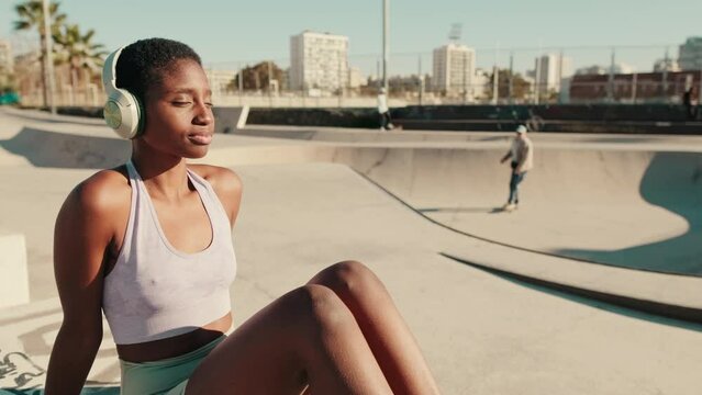 Close-up side view of a fit girl listening to music on headphones with eyes closed 
