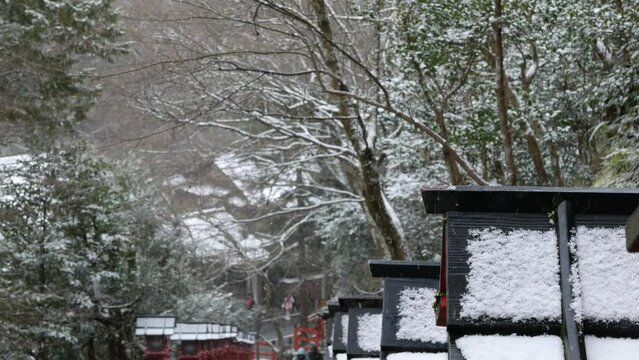 snow falling on the traditonal wooden lantern along rocky stair pathway in shrine temples in Kurama mountain of kyoto