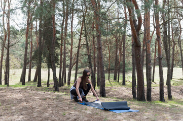 A young woman is preparing to practice yoga in the forest.