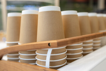 A wooden tray with many brown paper cups on it