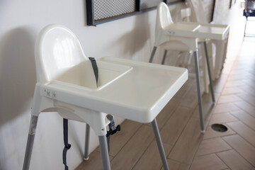 Two white high chairs are sitting next to each other on a tile floor