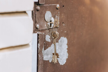 Metal old peeled rusty gate doors with a key in the keyhole. Close-up photography, retro architecture concept.