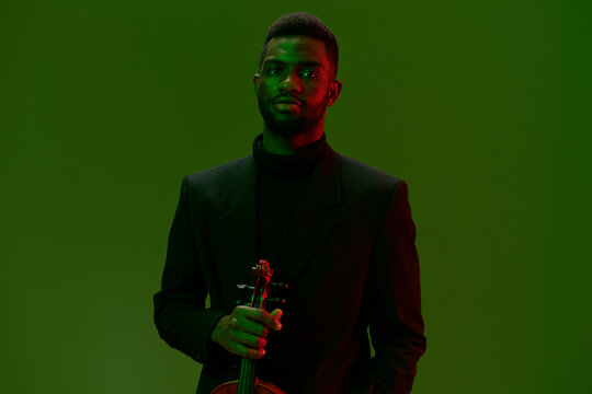 Elegant man in suit playing violin in front of green screen on black background - Powered by Adobe
