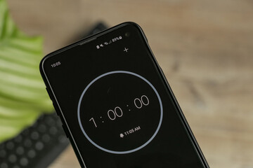 A phone with a black and white 1-hour timer to study with the pomodoro method on a blurry background. Perfect for students planning their time studying, doing homework, being productive.