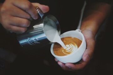 Barista pouring milk  into a coffee mug