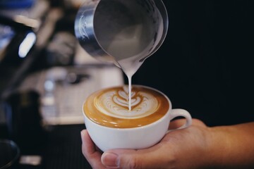 Barista pouring milk  into a coffee mug 