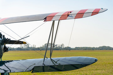 Wings of an old biplane with a grass runway in the background