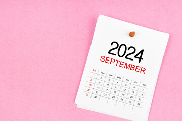 September 2024 calendar page and wooden push pin on pink background.